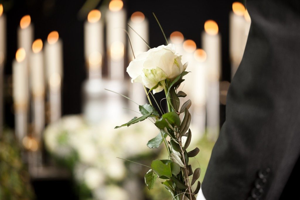 Man holding a white rose in a funeral