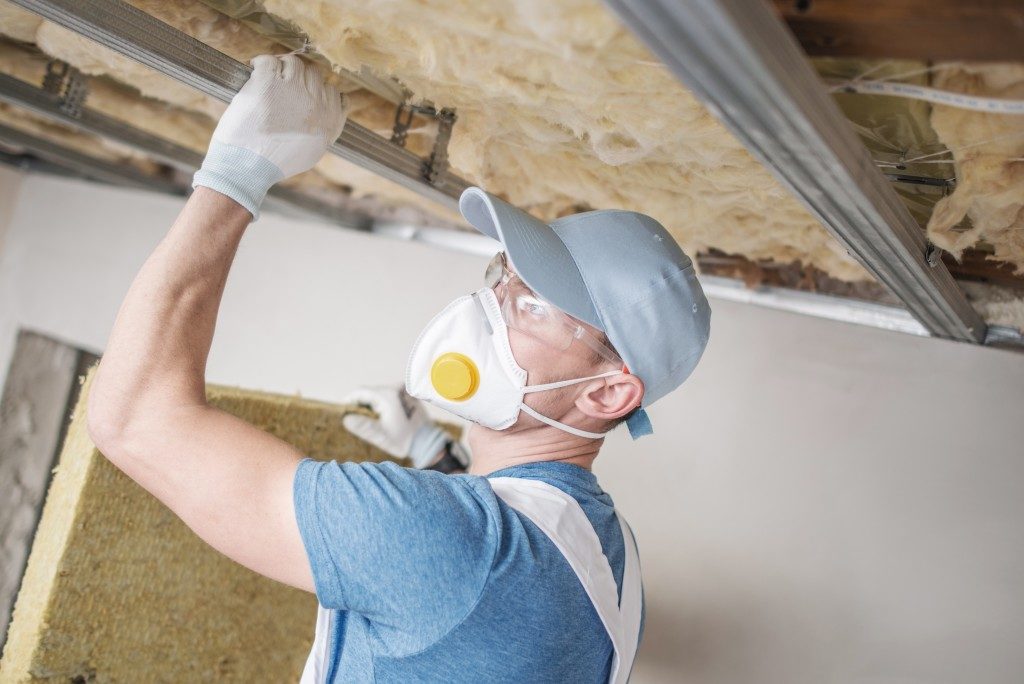 man applying insulation to ceiling