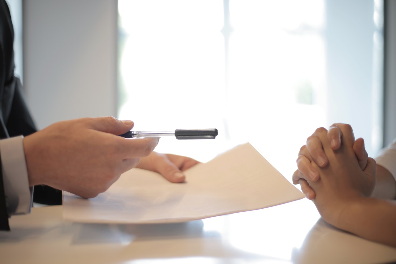 person handing a pen to another person